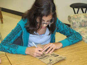 Rachel creating art and writing on her paper bag.